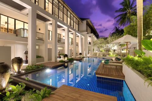 a swimming pool in front of a building at OUTRIGGER Surin Beach Resort in Surin Beach