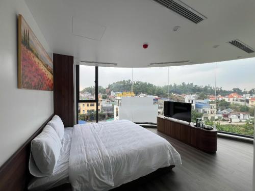 a bedroom with a white bed and a large window at Sora Hotel in Thường Son