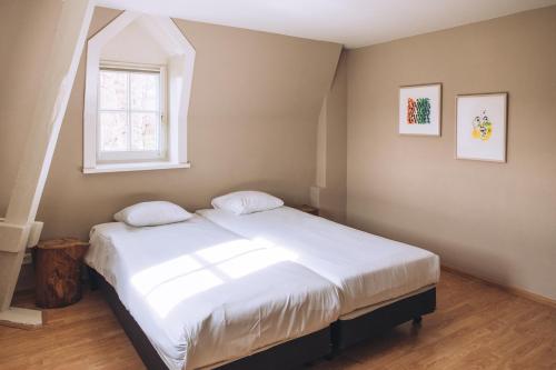 a bedroom with a white bed with a window at Portierswoning Vaeshartelt in Maastricht