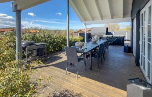 a deck with a table and chairs and a grill at Nice Home In Grenaa With Sauna in Grenå