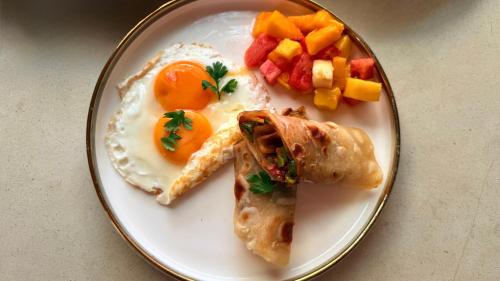a plate of breakfast food with eggs and fruit at The 5th Element Boutique Hotel in Paje