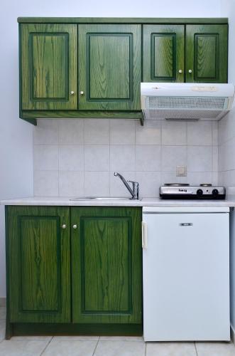 a kitchen with green cabinets and a white refrigerator at Onar Studios in Koufonisia