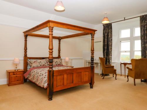a bedroom with a wooden canopy bed and a table at Dowrich West Wing Apartment in Crediton