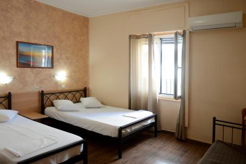a small room with two beds and a window at Electra Hotel Piraeus in Piraeus