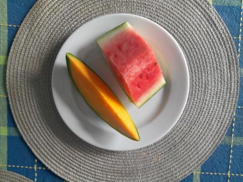 a plate with a slice of watermelon and a pickle at Résidence Belle Place Palmier in Saint-François