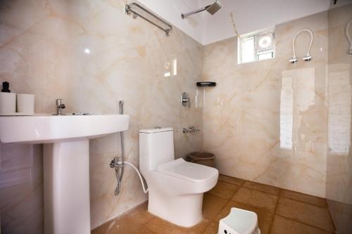 ein Badezimmer mit weißer Toilette und Waschbecken in der Unterkunft The Nest Bettathur, Coorg in Madikeri