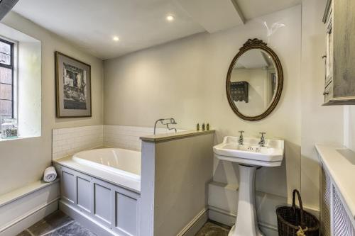 a bathroom with a tub and a sink and a mirror at Apple Cottage in Snowshill