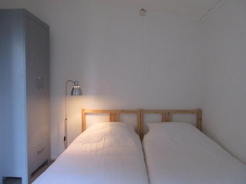 two beds in a room with white walls and a lamp at Zeealsem in Ballum