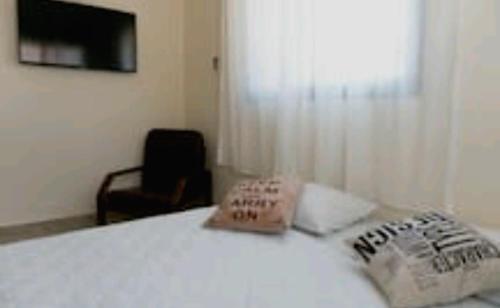 1 dormitorio con 1 cama, 1 silla y TV en Ilana's Place, en Qiryat H̱aroshet