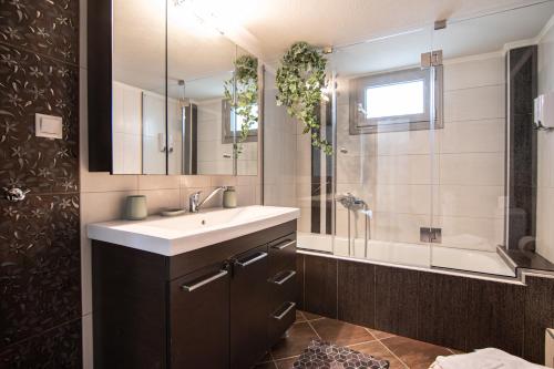 a bathroom with a sink and a mirror and a tub at Alexandra Boutique Residence VILLAS in Alexandroupoli