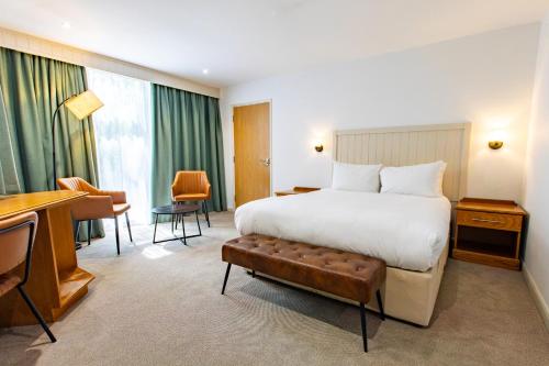 a hotel room with a large bed and a desk at Marwell Hotel Winchester South in Winchester