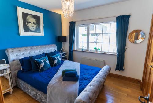 a blue bedroom with a bed and a window at Foxhill - Valentia in Valentia Island