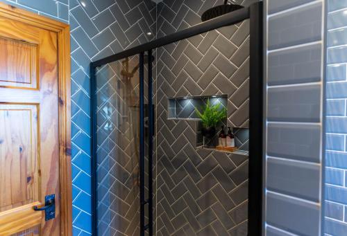 a shower in a bathroom with blue tiles at Foxhill - Valentia in Valentia Island