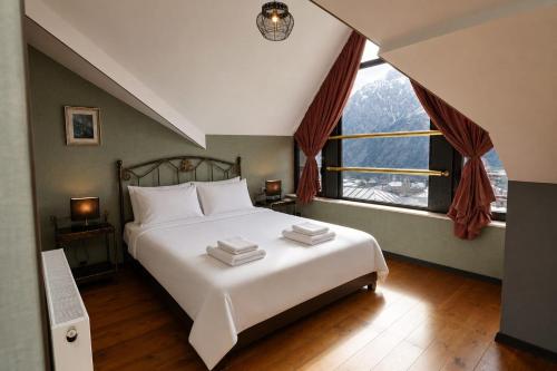 a bedroom with a large bed and a large window at Hilltop Kazbegi in Kazbegi