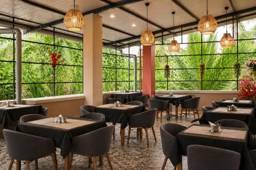 a restaurant with tables and chairs and large windows at Hotel L ! M Calangute Beach Way in Calangute