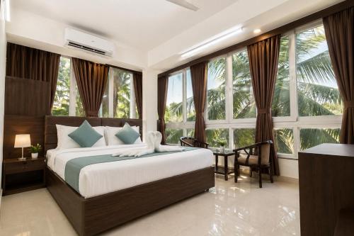 a bedroom with a bed and a desk and windows at Hotel L ! M Calangute Beach Way in Calangute