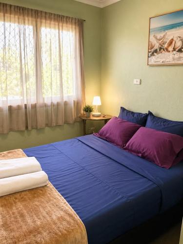a bedroom with a large blue bed and a window at Leimalo's Bungalow in Port Vila