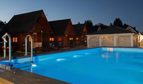a large swimming pool in front of a house at Domki Maks in Bobolin