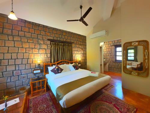 a bedroom with a bed and a brick wall at Tiger Trails Resort in Tāla