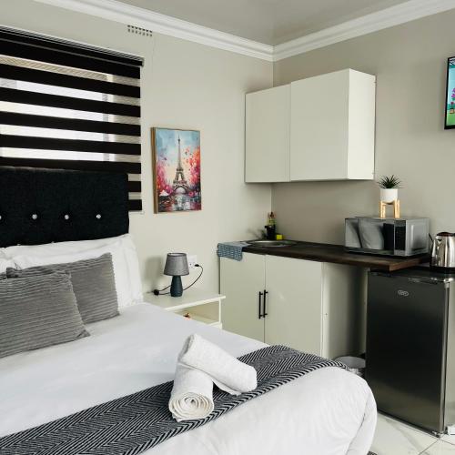 a bedroom with a white bed and a kitchen at 4 at Granada 1 in East London
