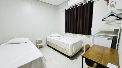 a room with two beds and a table in it at Nathus Hotel in Chapadão do Sul