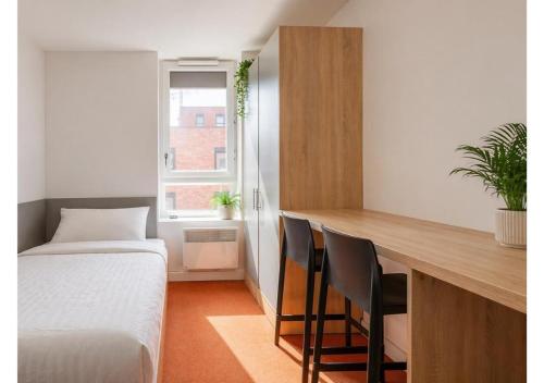 a bedroom with a bed and a desk with chairs at Globeworks by UTDM in Birmingham
