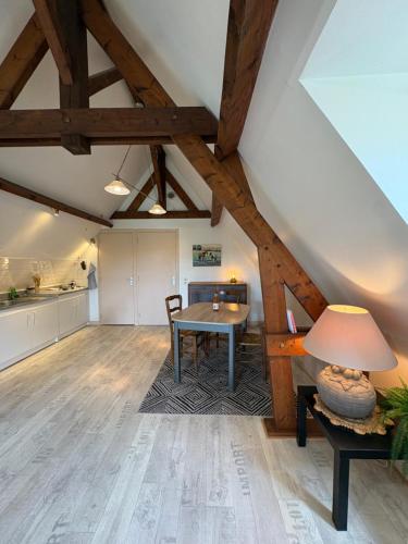 an attic living room with a table and a kitchen at Le Cottage in Cambremer