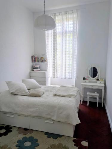 a white bedroom with a bed and a window at Passage Foch centre historique in Perpignan