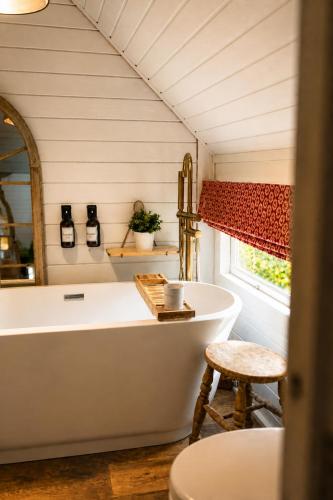 a bathroom with a tub and a stool and a window at 2 - Luxury Escape - Outdoor bathtub and sauna under the stars! in Pont Sticill