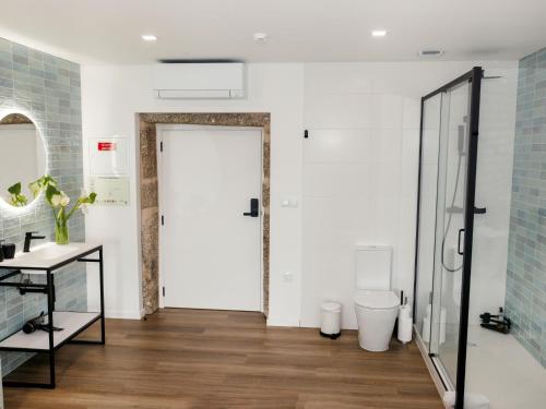 a bathroom with a toilet and a glass door at Quinta Cerca da Milhera in Ponte da Barca
