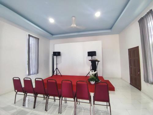 a dining room with a red table and red chairs at CD Garden Cottage in Kota Bharu