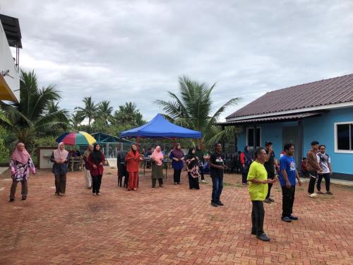 a group of people standing outside a blue building at CD Garden Cottage in Kota Bharu