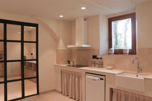 a white kitchen with a sink and a window at Mas Les Arrabassades in Castelló d'Empúries