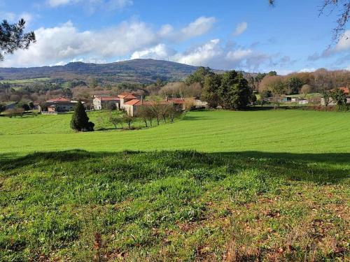 a large green field with a house in the distance at Casa da Torreira Naturaleza y descanso in Galegos