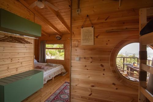 a bedroom in a log cabin with a bed and a window at the Treehouse Project in Patra