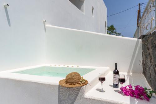 a table with a hat and wine glasses and a swimming pool at Sandy's Paradise- Adults Only in Perissa