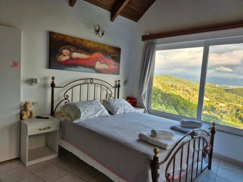 a bedroom with a bed and a large window at Baso Hilltop Apartments in Argassi