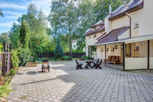 a patio area with chairs, tables, and a bench at Drusva Apartamentai in Druskininkai