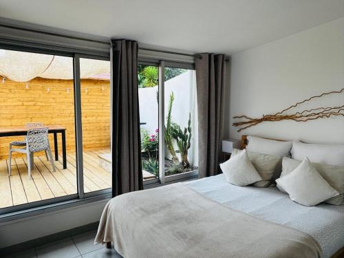 a bedroom with a bed and a balcony with a table at Gîte Les Lauriers Roses in Marseillan