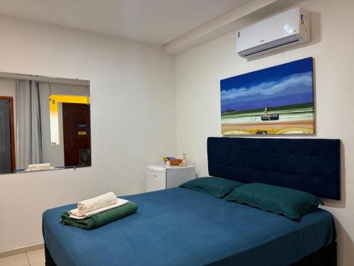 a bedroom with a blue bed with a painting on the wall at Ruta Del Sol in Mossoró