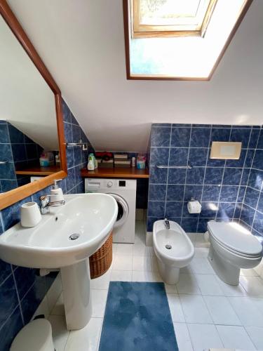 a blue tiled bathroom with a sink and a toilet at Orizzonte guest house in Laigueglia