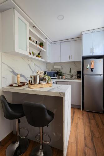 a kitchen with white cabinets and a black refrigerator at Escondite de Amor in La Vega