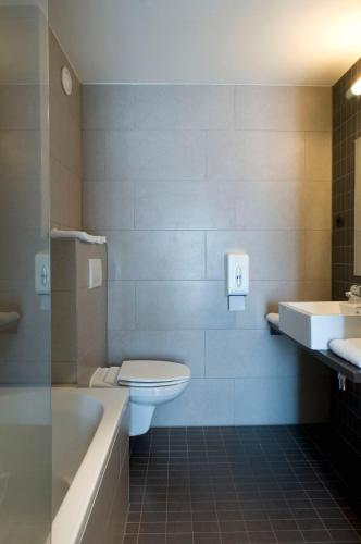 a bathroom with a toilet and a tub and a sink at Ibis Styles La Louvière in La Louvière