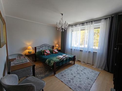 a bedroom with a bed and a chair and a chandelier at MAREA rooms in Jantar