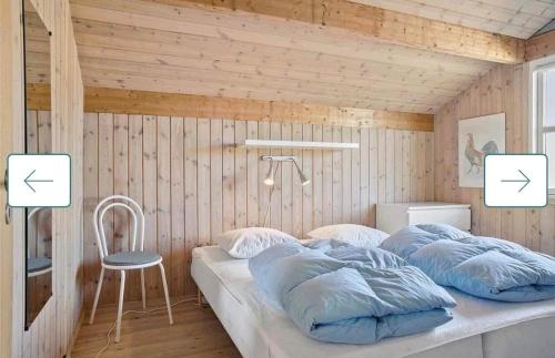 a bedroom with a bed with two pillows and a chair at Feriehus Kornblomst in Tversted