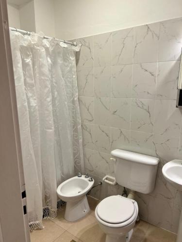a white bathroom with a toilet and a sink at Alojamiento Guemes II in San Fernando del Valle de Catamarca