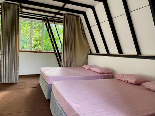 two beds in a room with two windows at Doranagala Holiday Cabin in Rattota