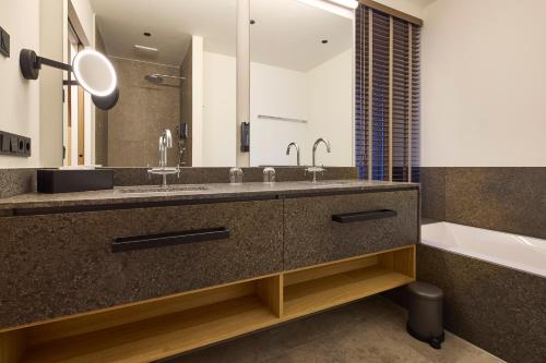 a bathroom with a sink and a tub and a mirror at Das Lakeside - Move&Relax in Walchsee