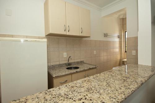a kitchen with a counter and a sink and a refrigerator at Pousada Vale Del Sol in Bombinhas