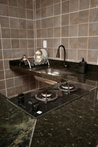 a kitchen counter with a stove and a sink at Apartamento 2 Vargem Grande RJ in Rio de Janeiro
